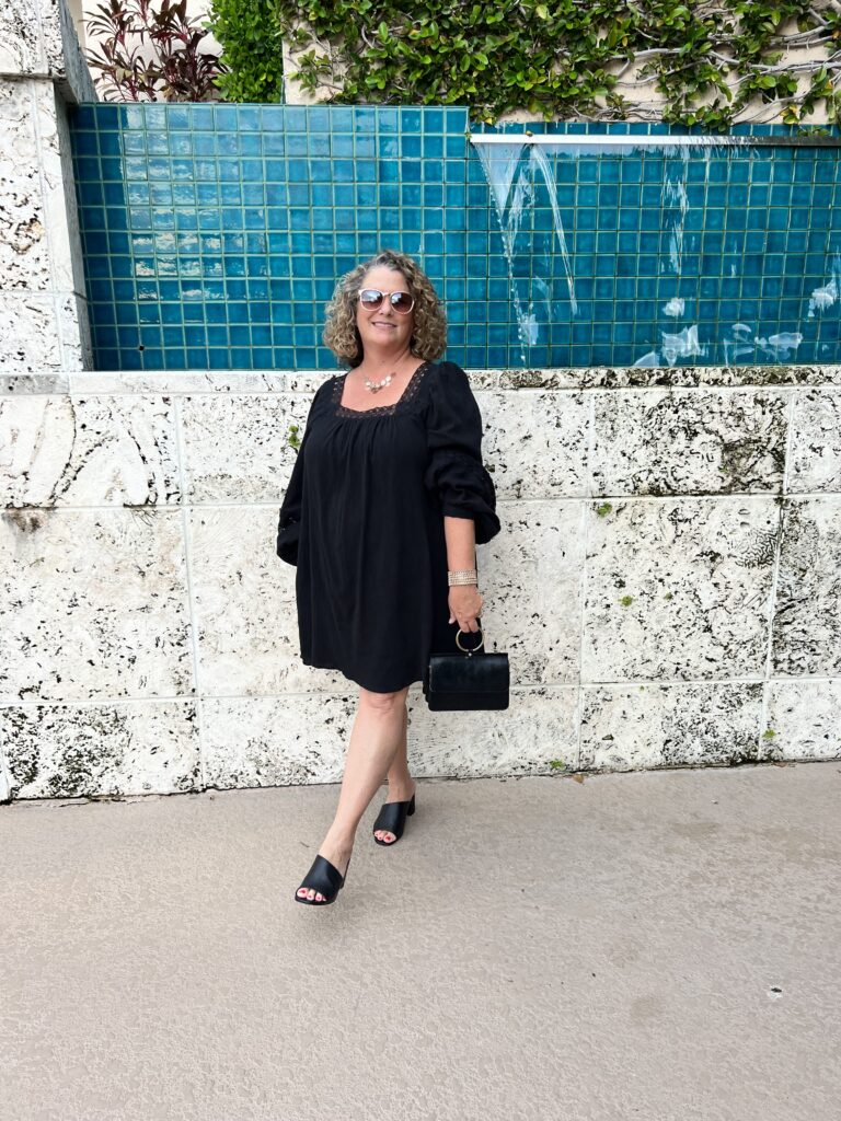 April standing in front of a wall in a black dress and sunglasses