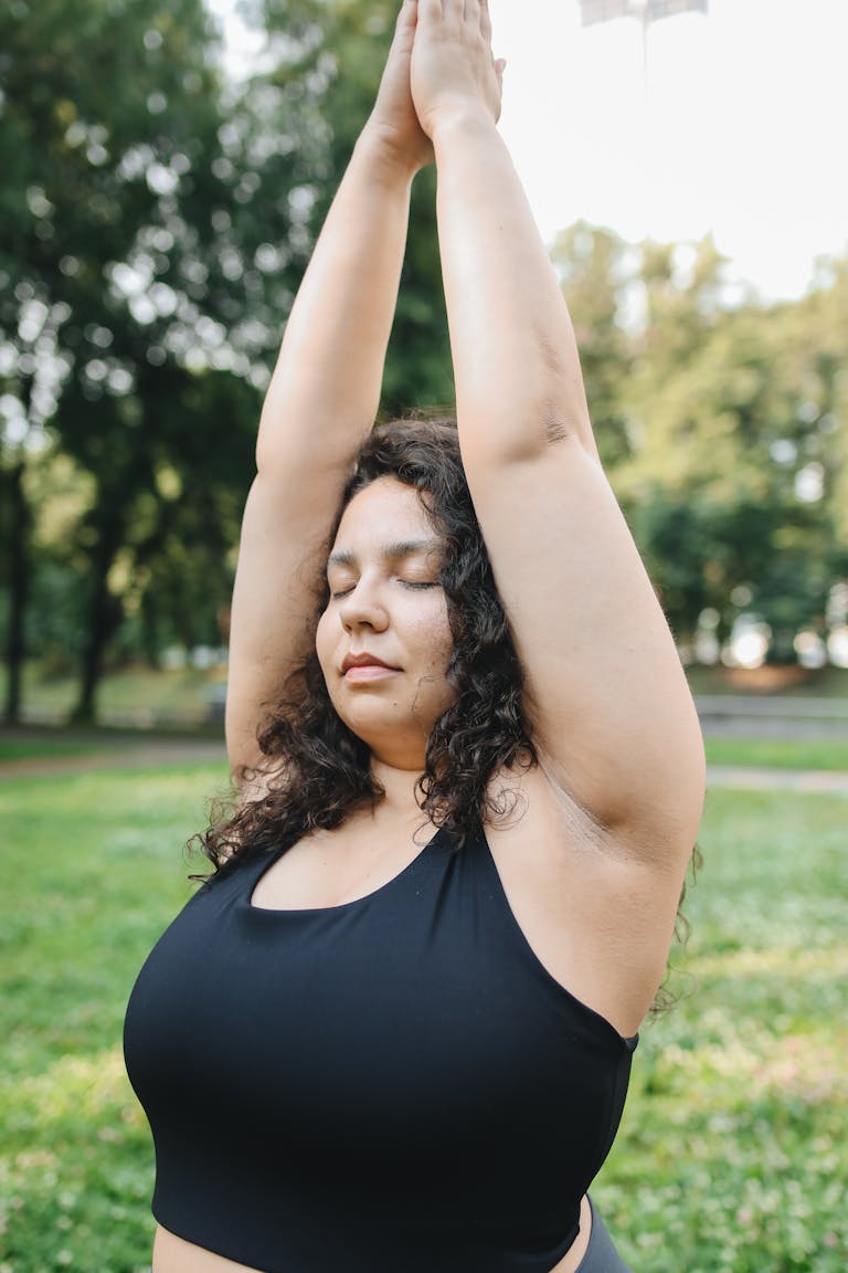 A Woman in Black Tank Top Raising Her Hands