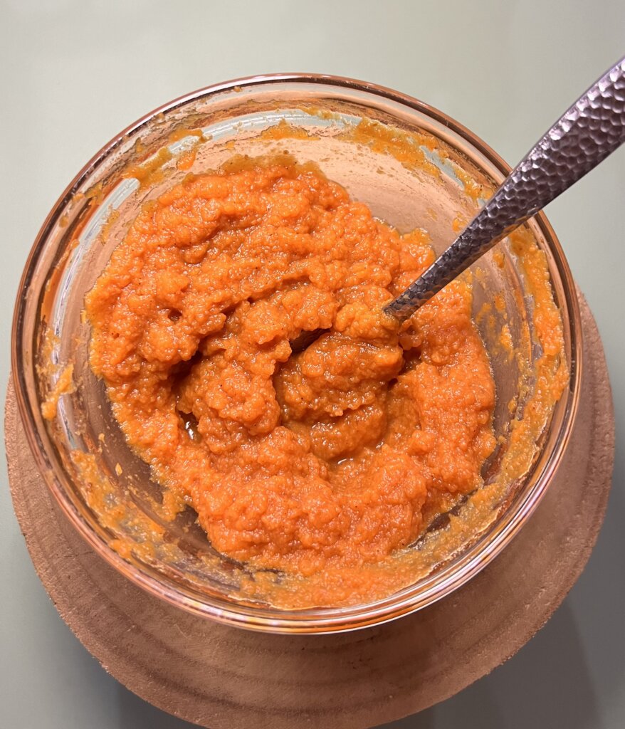 glass bowl with pumpkin beauty face mask ingredients and a metal spoon