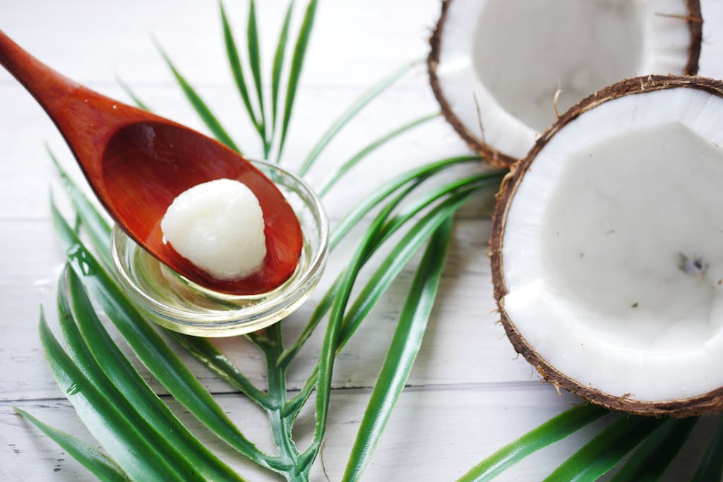 Coconut cut in half with hardened coconut oil on a wooden spoon