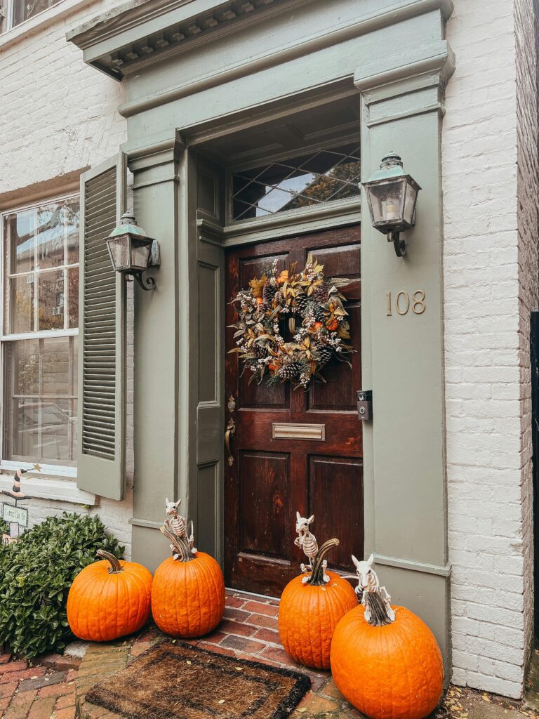 four orange pumpkins flanking a doorstep