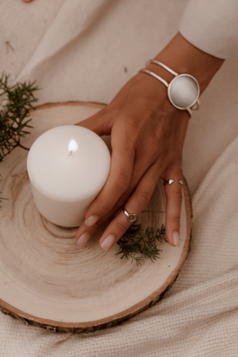 a hand placing a lighted non toxic candle on a dish