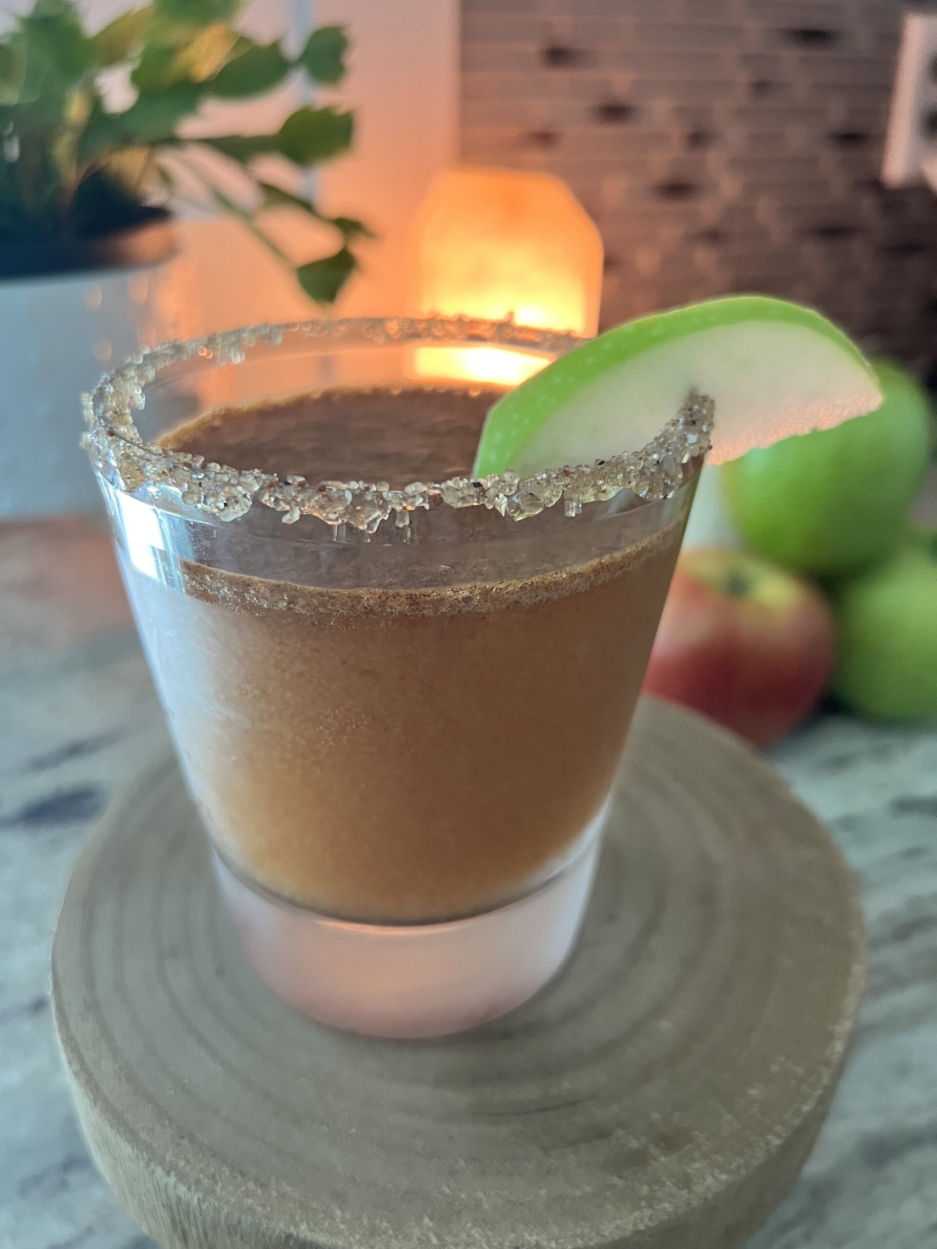 sugar rimmed glass with brown drink and sliced apple garnish