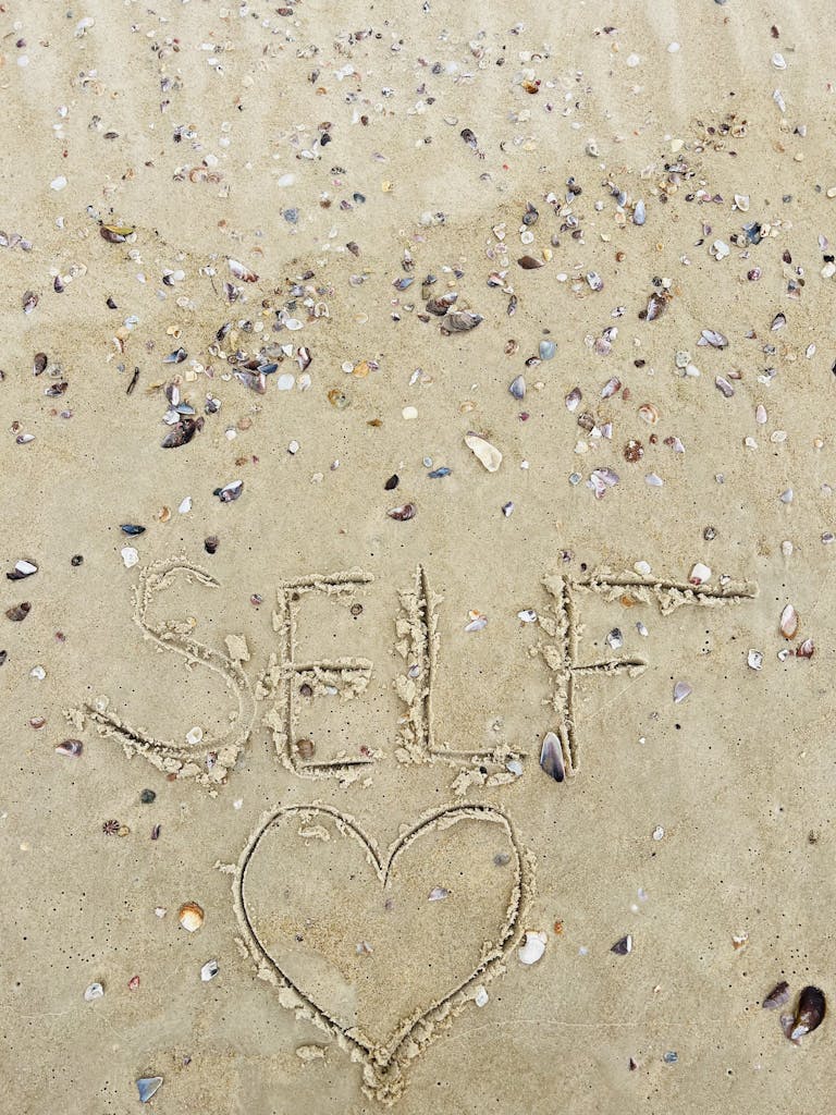 reclaiming life by drawing the words SELF in sand with a heart