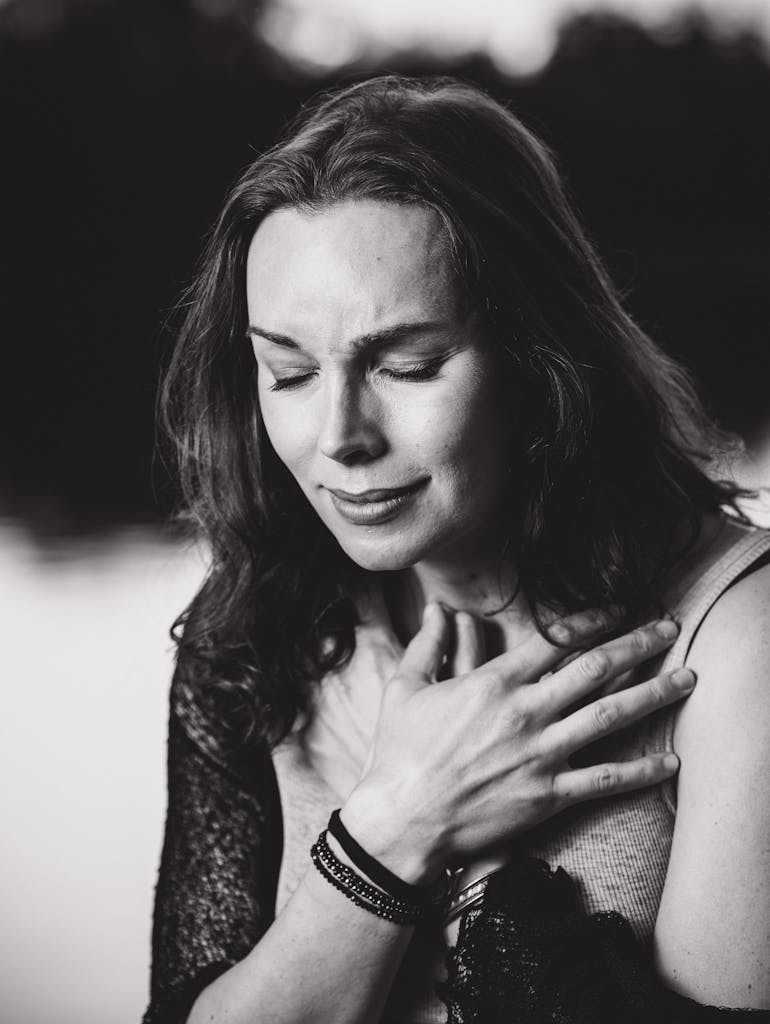 A dramatic black and white portrait capturing a woman's emotional expression outdoors.