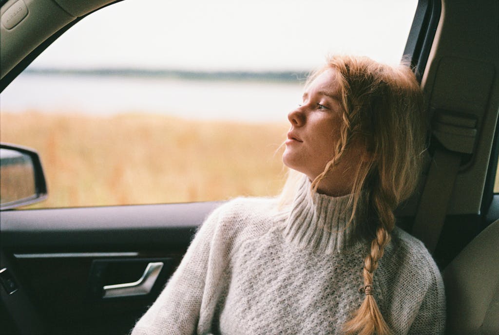 A thoughtful woman taking a break in a car, gazes out a car window and thinking about her feelings
