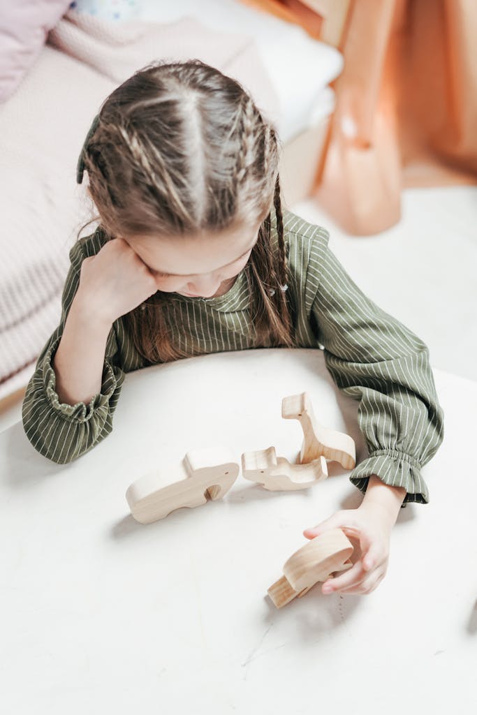 Young girl plays with wooden toys alone in her room as she tries to process emotions